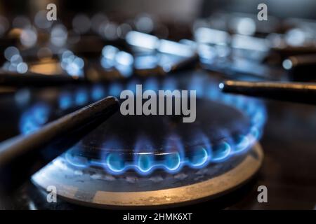 Gros plan des anneaux à gaz flamboyants allumés sur la table de cuisson d'une cuisinière à gaz domestique dans une cuisine britannique. Banque D'Images