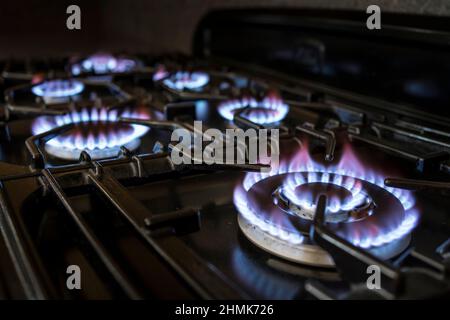 Gros plan des anneaux à gaz flamboyants allumés sur la table de cuisson d'une cuisinière à gaz domestique dans une cuisine britannique. Banque D'Images