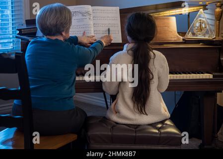 South Jordan, Utah, États-Unis, 10 février 2022. Une belle jeune étudiante de piano se concentre sur sa leçon. Son professeur la surveille à chaque mouvement. Banque D'Images