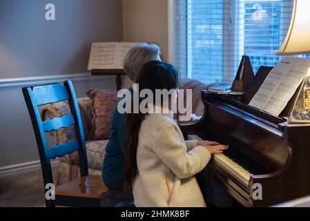 South Jordan, Utah, États-Unis, 10 février 2022. Une belle jeune étudiante de piano se concentre sur sa leçon. Son professeur la surveille à chaque mouvement. Banque D'Images