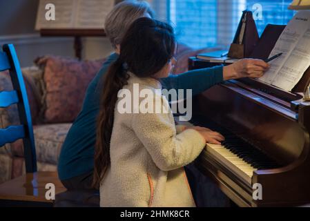 South Jordan, Utah, États-Unis, 10 février 2022. Une belle jeune étudiante de piano se concentre sur sa leçon. Son professeur la surveille à chaque mouvement. Banque D'Images