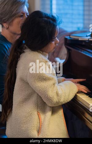 South Jordan, Utah, États-Unis, 10 février 2022. Une belle jeune étudiante de piano se concentre sur sa leçon. Son professeur la surveille à chaque mouvement. Banque D'Images