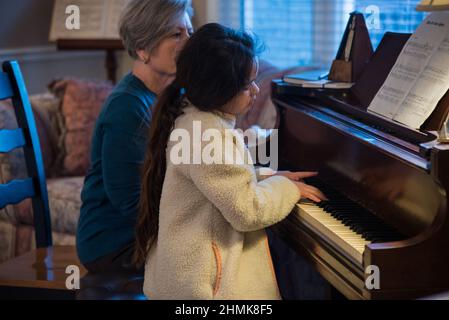 South Jordan, Utah, États-Unis, 10 février 2022. Une belle jeune étudiante de piano se concentre sur sa leçon. Son professeur la surveille à chaque mouvement. Banque D'Images