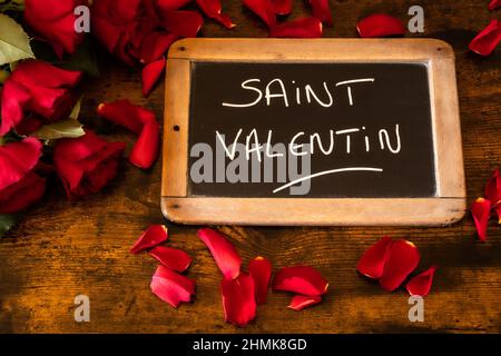 inscription du jour de la saint-valentin sur une ardoise avec des roses sur un fond en bois Banque D'Images