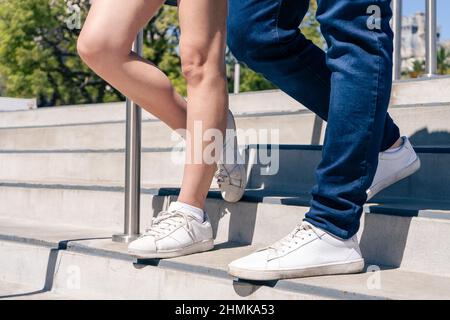 Un couple caucasien ou hispanique méconnaissable en tenue décontractée marchant dans un escalier en béton. Orientation horizontale. Banque D'Images