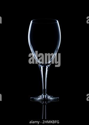 Verre à vin blanc cristal vide sur surface réfléchissante noire avec rebord lumineux Banque D'Images