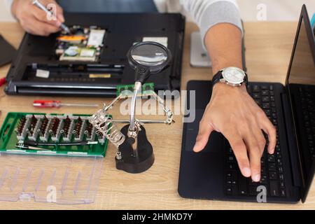 un réparateur démontant la carte mère de l'ordinateur portable Banque D'Images