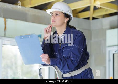 géomètre femelle en casque dur pendant l'inspection de la maison Banque D'Images