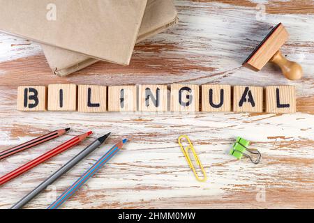 Bilingue. Manuels scolaires, papeterie et timbre en bois sur la table. Banque D'Images