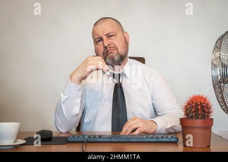 L'homme décrit comiquement le travail d'un homme d'affaires. Il montre son mécontentement sur son visage et sa posture. Banque D'Images