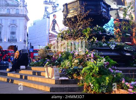 Des plantes et des fleurs couvrent la fontaine commémorative Shaftesbury, souvent connue sous le nom d'« Eros », à Piccadilly Circus, Londres, Angleterre, Royaume-Uni. Pour une journée le 10th février 2022, cette annonce a annoncé une expérience de réalité augmentée Green Planet qui a ouvert ses portes à Piccadilly Circus le 11th février 2022. Parmi les partenaires et les partisans de ce projet figurent BBC Earth, EE, Crown Estate, Factory 42, Kew Royal Botanic Gardens, Talesmith et dimension. Le projet propose la réservation de billets gratuits en ligne et dure jusqu'au 9th mars 2022. Les gens s'assoient sur la statue et profitent du soleil de la fin de l'après-midi. Banque D'Images