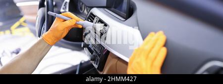 Master nettoie le système de ventilation dans la voiture avec une brosse de gros plan Banque D'Images