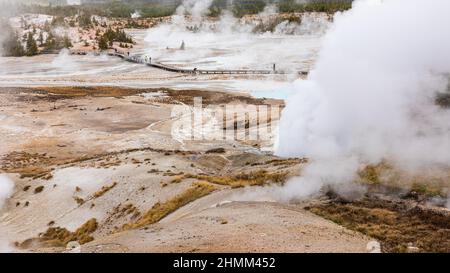 Vue aérienne de la zone chaude couverte par la fumée de soufre du geyser avec le fond des touristes sur la promenade à l'intérieur de la zone de Old Faithful à Yellowstone, Wyo Banque D'Images