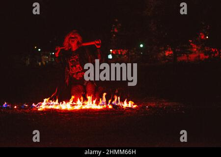 Portrait de la jeune femme blonde élégante grunge avec le club près du feu Banque D'Images