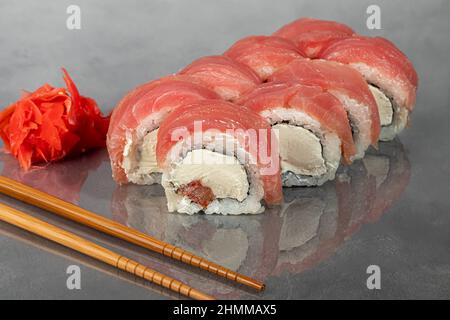 Les sushis Uramaki, Californie, Philadelphie, roulent sur une assiette blanche. Menu pour les restaurants, cafés. Sur un arrière-plan réfléchissant foncé. Espace de copie Banque D'Images