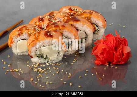 Les sushis Uramaki, Californie, Philadelphie, roulent sur une assiette blanche. Menu pour les restaurants, cafés. Sur un arrière-plan réfléchissant foncé. Espace de copie Banque D'Images