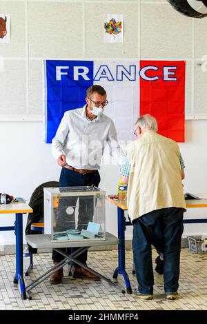 Neuville-es-Dieppe (nord de la France), le 20 juin 2021 : bureau de vote pour les élections départementales et régionales de l'école primaire Òcole Paul LangevinÓ. Assesseurs, urnes et drapeau tricolore français, bleu, blanc et rouge, avec l'inscription ÒFranceÓ. Personne âgée pendant le vote Banque D'Images