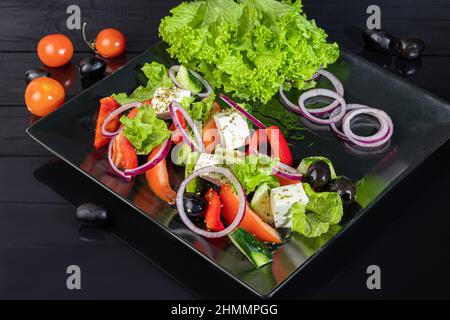 Salade grecque avec feta, tomates, olives et laitue. Sur un arrière-plan sombre. Espace de copie Banque D'Images