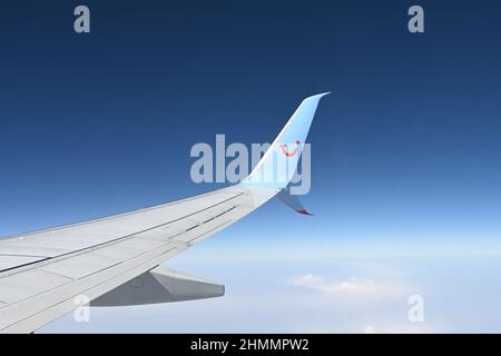 Une aile d'un Boeing 737 TUI affrété avion pris en vol montrant la clarté du ciel bleu et des nuages dispersés ci-dessous Banque D'Images