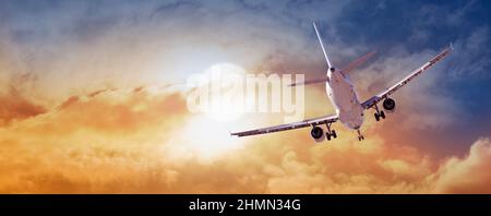 Passagers avion commercial survolant les nuages dans la lumière du coucher du soleil. Banque D'Images