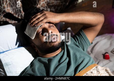 jeune indien malade souffrant de fièvre légère pendant le sommeil de nuit - concept de soins de santé, symptômes de covid et de maladie. Banque D'Images