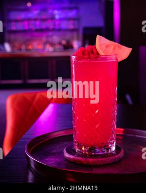 Cocktail alcoolisé Tutti Frutti garni de framboises et de tranches de citron au bar Banque D'Images