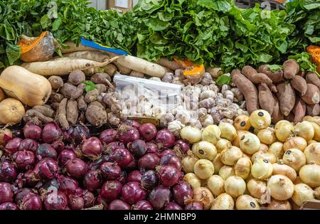 Différents types d'oignons et de pommes de terre sont vendus à un marché Banque D'Images