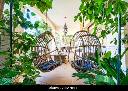 une image d'une paire de chaises suspendues sur la terrasse du jardin d'une villa Banque D'Images