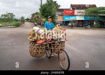 Province de Binh Dinh, Vietnam - 3 janvier 2022 : un agriculteur vend des poêles faits à la main qui sont transportés sur une vieille bicyclette dans la province de Binh Dinh, Vietnam Banque D'Images