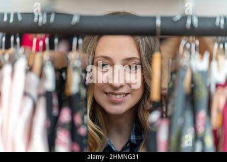 Femme blonde enceinte à la recherche de vêtements dans un magasin de vêtements Banque D'Images