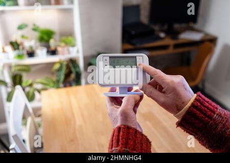 Point de vue prise de vue d'un homme méconnaissable tenant un thermostat dans sa maison. Banque D'Images