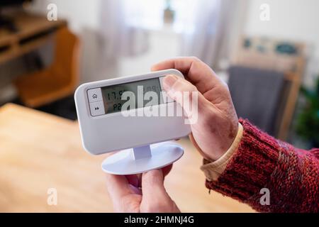 Point de vue prise de vue d'un homme méconnaissable tenant un thermostat dans sa maison. Banque D'Images