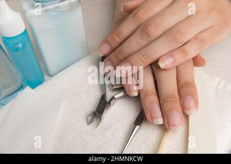 Les mains des femmes sur une serviette. Manucure. Outils de manucure, vernis à ongles. Soins des ongles à domicile, SPA, beauté. Ongles naturels longs. Salon de beauté. Banque D'Images