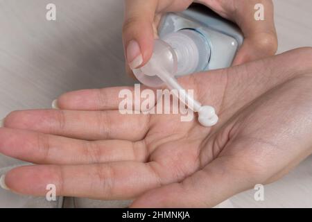 Femme tenant le tube de crème et appliquant la crème hydratante sur ses belles mains pour une peau propre et douce. Arrière-plan blanc. Prenez soin de votre peau de corps. Banque D'Images