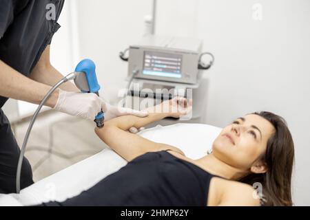 Le médecin applique un traitement par onde de choc sur le genou des femmes Banque D'Images