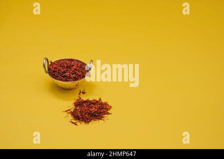 Les fils rouges de scarlet séchés stigmates de l'épice de sargol de safran biologique dans un bol à épices vintage sur fond jaune Banque D'Images