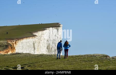 Eastbourne, Royaume-Uni. 11th février 2022 - Walkers Profitez d'une promenade le long de Beachy Head près d'Eastbourne sur une belle après-midi ensoleillé mais beaucoup de temps doux et humide est prévu pour les prochains jours au Royaume-Uni : crédit Simon Dack / Alamy Live News Banque D'Images