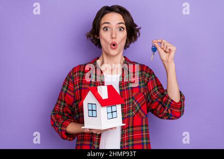 Photo de jeune brunette impressionnée dame tenir la maison porte-clés chemise rouge isolée sur fond de couleur pourpre Banque D'Images