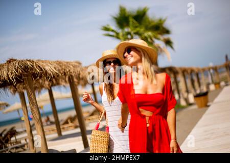 Deux jolies jeunes femmes marchant sur une plage en été Banque D'Images