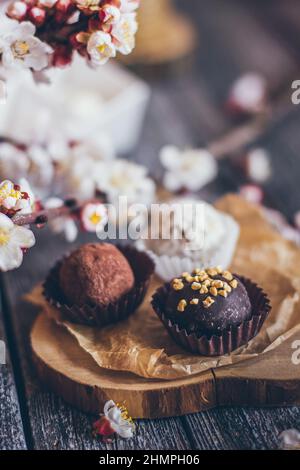 Collection printanière de bonbons au chocolat faits main bonbons et fleurs de cerisier décoration sur fond rustique en bois Banque D'Images