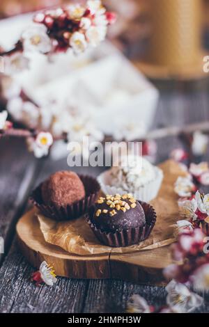 Collection printanière de bonbons au chocolat faits main bonbons et fleurs de cerisier décoration sur fond rustique en bois Banque D'Images