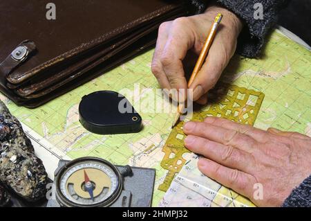 Le géologue travaille avec les cartes. Sur son bureau se trouvent: Cas de carte, boussole, loupe, échantillons de roche, cartes topographiques et géologiques Banque D'Images