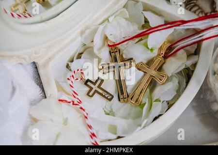 Trois petites croix de baptême d'or pendant le rituel du baptême dans l'église arménienne. Gros plan des croix d'or Banque D'Images