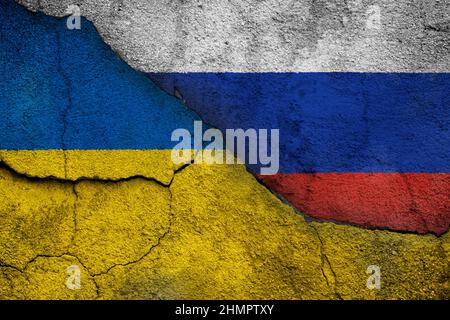 Photo plein cadre des drapeaux abîmés de l'Ukraine et de la Russie peints sur un mur fissuré. Concept de crise, de conflit et d'invasion Ukraine-Russie. Banque D'Images