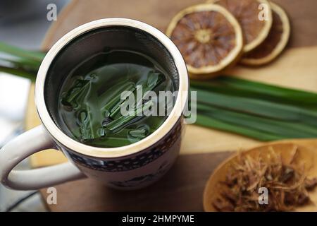 Goias, Brésil – 11 février 2022 : une tasse de thé, avec des feuilles de citronnelle, quelques tranches d'orange déshydratée, une cuillère avec des herbes. Banque D'Images