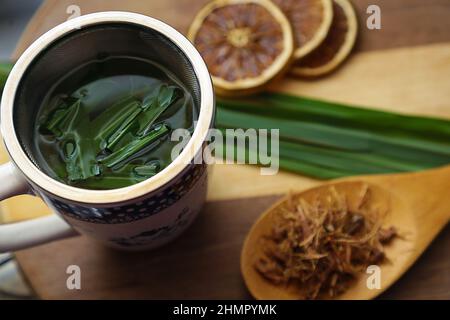 Goias, Brésil – 11 février 2022 : une tasse de thé, avec des feuilles de citronnelle, quelques tranches d'orange déshydratée, une cuillère avec des herbes. Banque D'Images