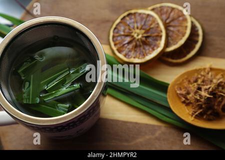 Goias, Brésil – 11 février 2022 : une tasse de thé, avec des feuilles de citronnelle, quelques tranches d'orange déshydratée, une cuillère avec des herbes. Banque D'Images