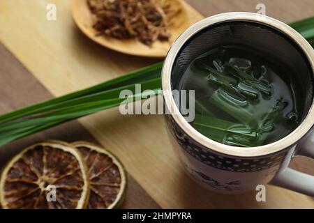 Goias, Brésil – 11 février 2022 : une tasse de thé, avec des feuilles de citronnelle, quelques tranches d'orange déshydratée, une cuillère avec des herbes. Banque D'Images