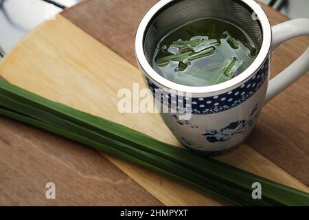Goias, Brésil – 11 février 2022 : une tasse de thé avec des feuilles de citronnelle sur une surface en bois. Banque D'Images