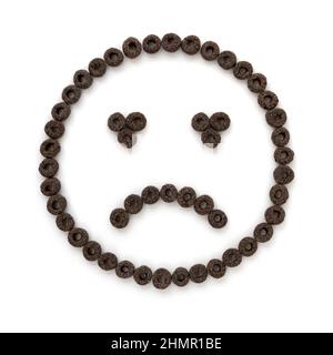 croquant céréales anneaux petit déjeuner en forme de visage triste sur fond blanc, concept de manger sain, céréales flocons, vue de dessus, gros plan Banque D'Images